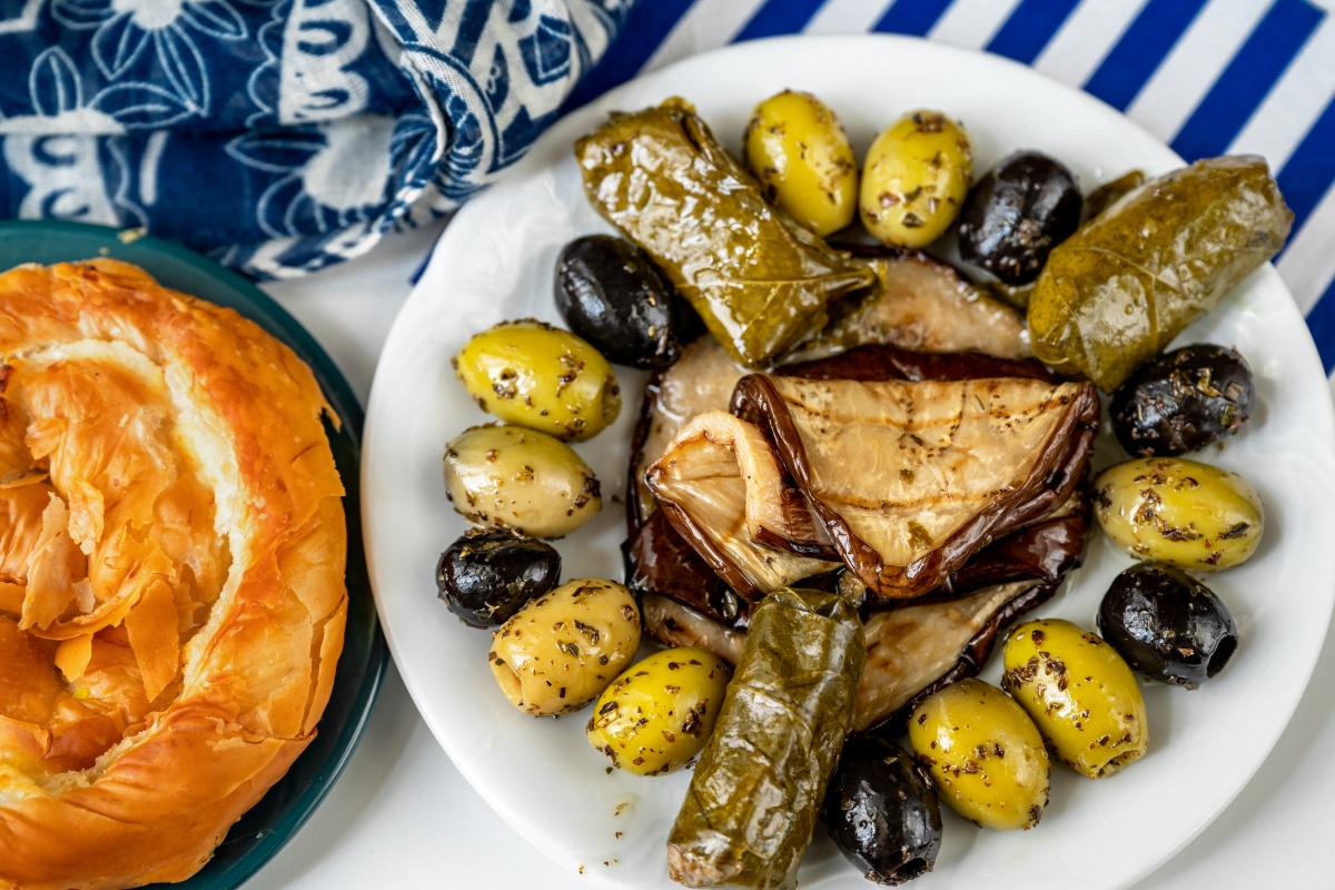 Ein griechisches Gericht mit Oliven, Weinblättern, Aubergine und Brot.