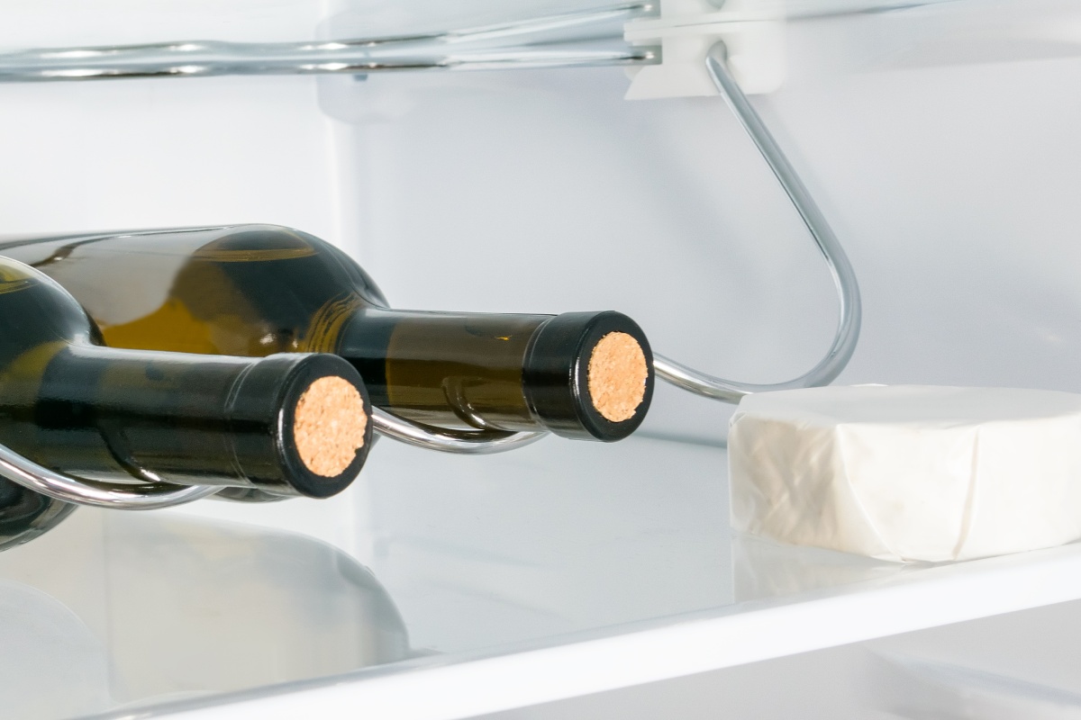 Zwei Weinflaschen un ein Stück Käse im Kühlschrank.