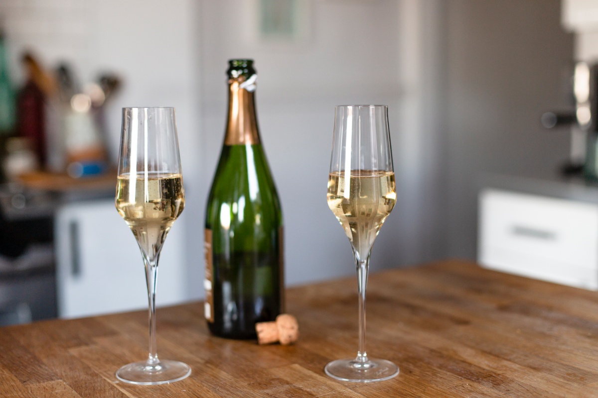 Zwei Sektgläser stehen neben einer Sektflasche auf einem Küchentisch.