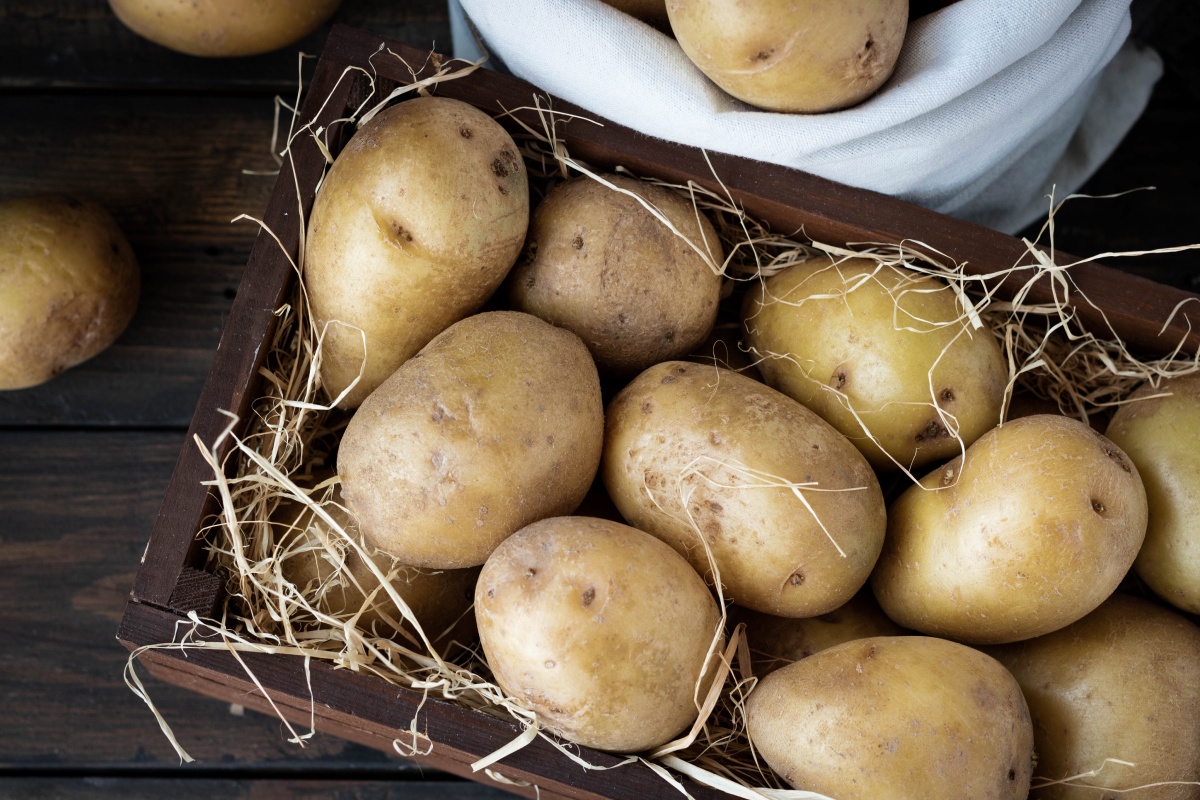 Kartoffeln in einer Holzkiste mit Stroh, ideal für die Lagerung im Keller.