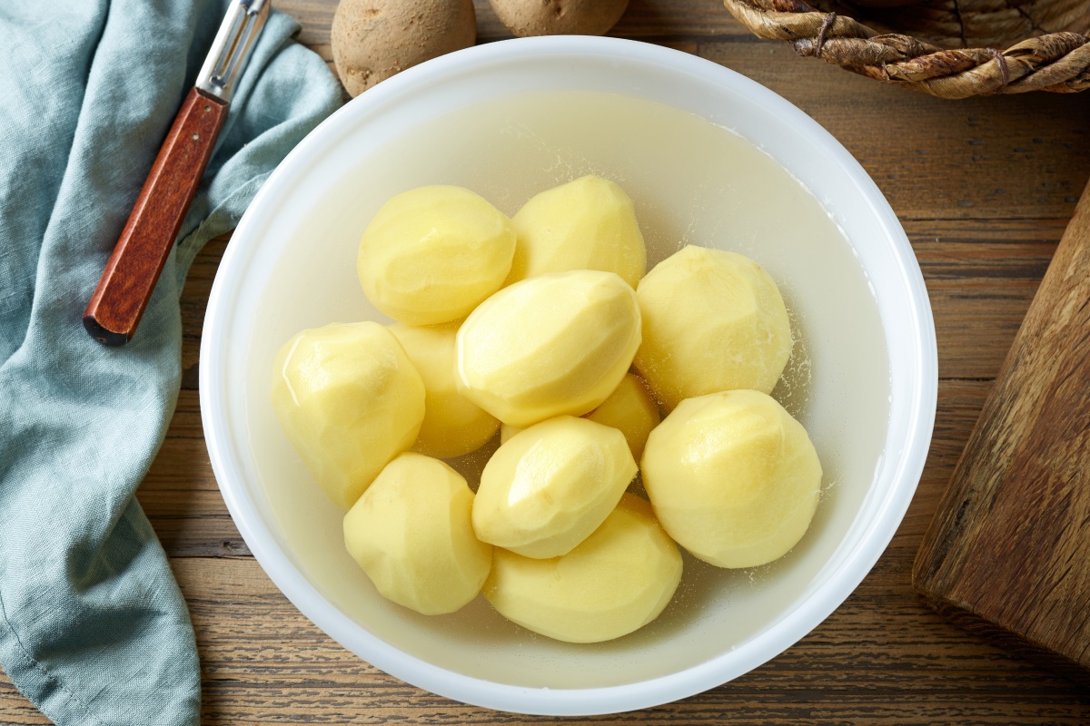 Geschälte Kartoffeln in einer Schüssel mit Wasser, bereit zur Aufbewahrung im Kühlschrank.
