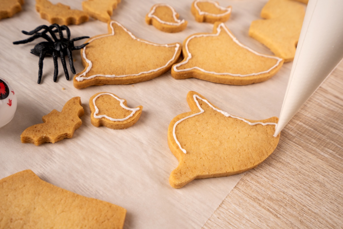 Plätzchen in Geister- und Fledermausform werden mit weißem Zuckerguss verziert.