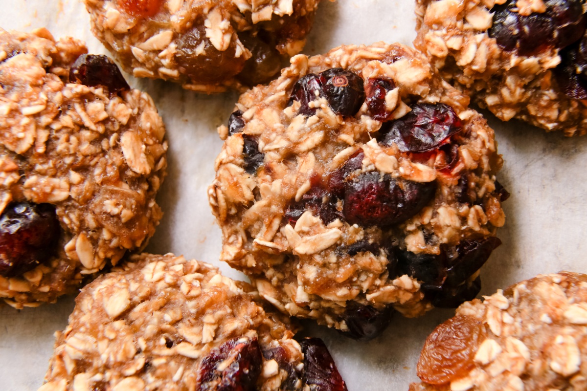 Haferflockenplätzchen mit Trockenfrüchten wie Cranberries und Aprikosen, frisch gebacken auf Backpapier arrangiert.