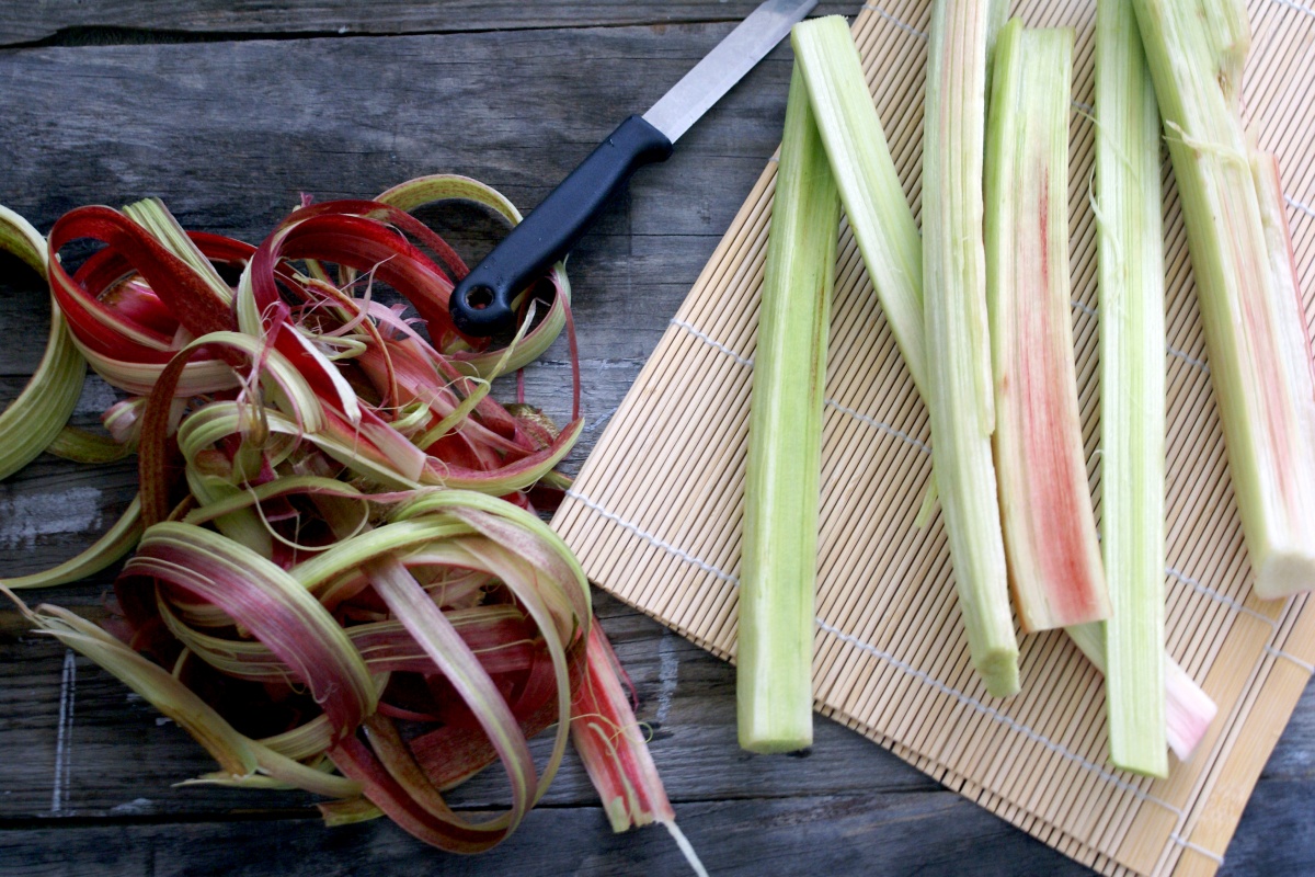 Geputzte Rhabarberstangen auf einer Bastunterlage. Daneben die Schale der Rhabarberstangen.