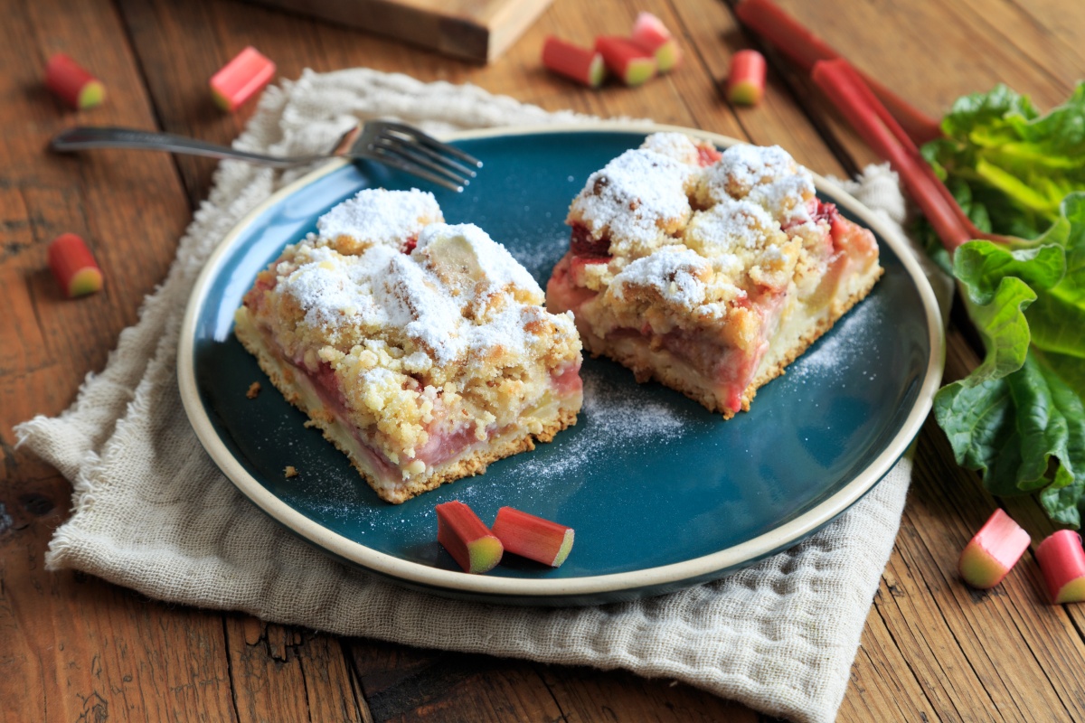 Zwei Stücke Rhabarberkuchen mit Streuseln auf einem blauen Kuchenteller.