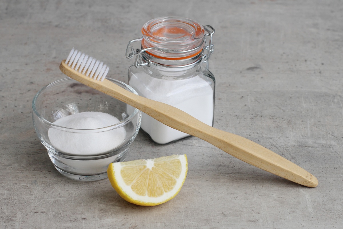 Zitrone, Salz, Backpulver und eine Zahnbürste liegen bereit, um Flecken zu entfernen.