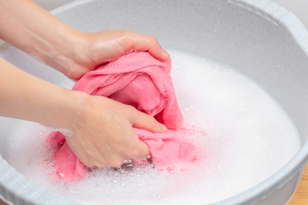 Eine Person wäscht ein rosa farbenes Kleidungsstück in einer Schüssel mit Gallseife.