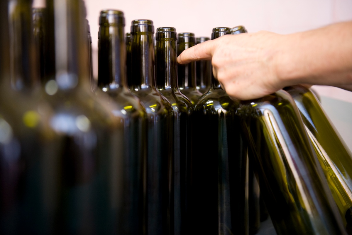 Reihe von leeren grünen Weinflaschen, eine Hand greift nach einer der Flaschen.