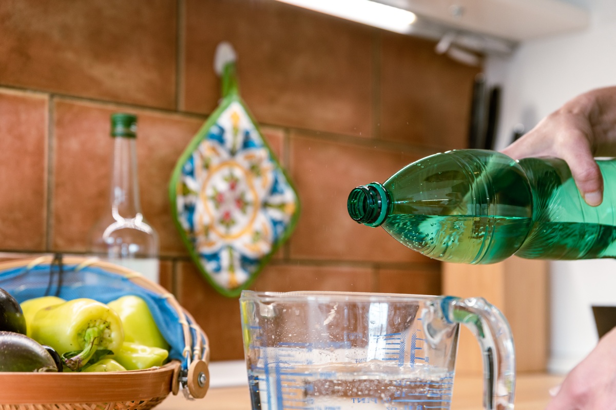 Eine Person füllt Wasser in ein Behältnis um aus dem Wein Essig anzusetzen.