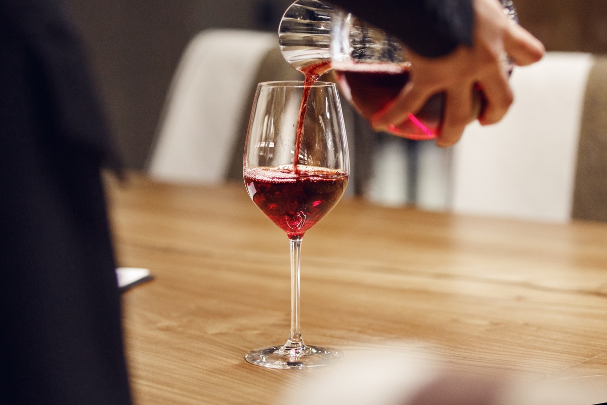 Rotwein wird aus einer Karaffe in ein Weinglas gegossen, um den Wein zu dekantieren.