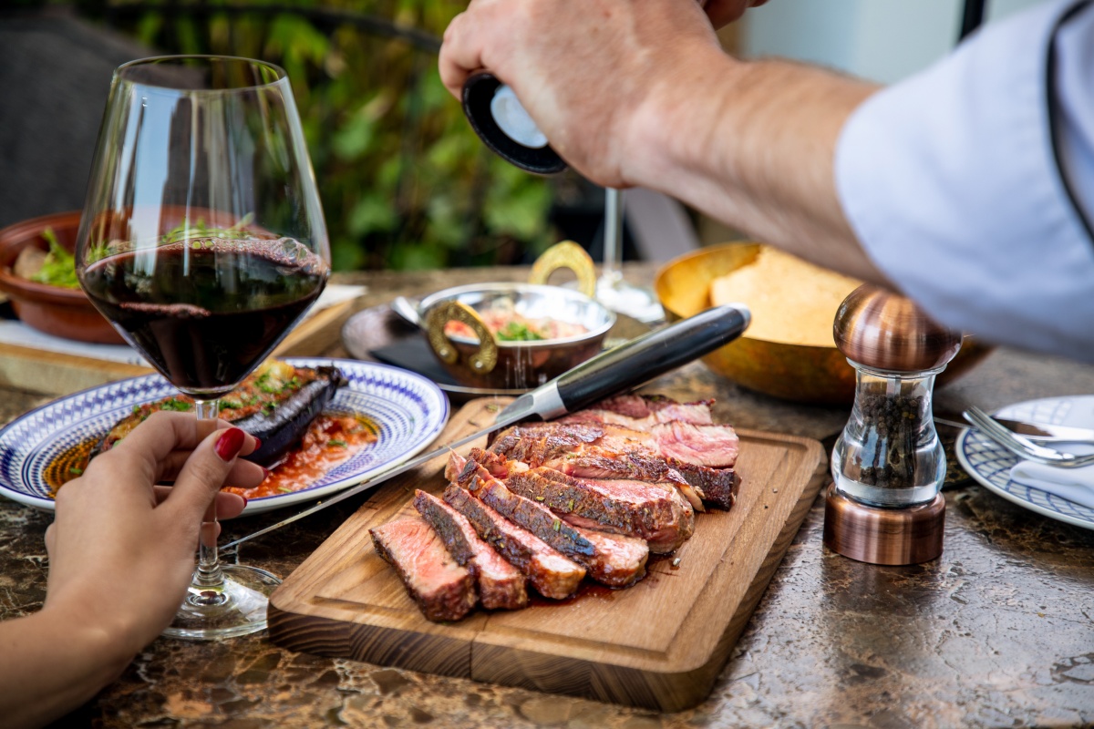 Eine Frau hält ein Rotweinglas an einem reich gedeckten Tisch.