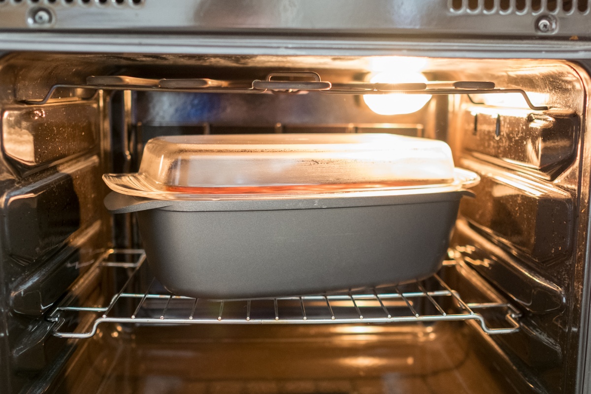 Eine graue Auflaufform mit gläsernem Deckel im Backofen.