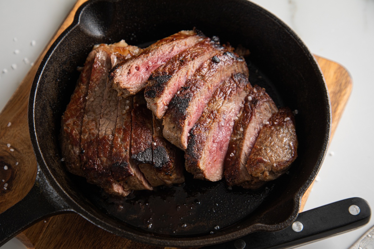 Eine gusseiserne Pfanne mit aufgeschnittenem Steak.