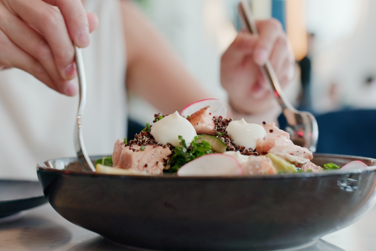 Eine Person mischt einen Salat in einer Porzellanschale.