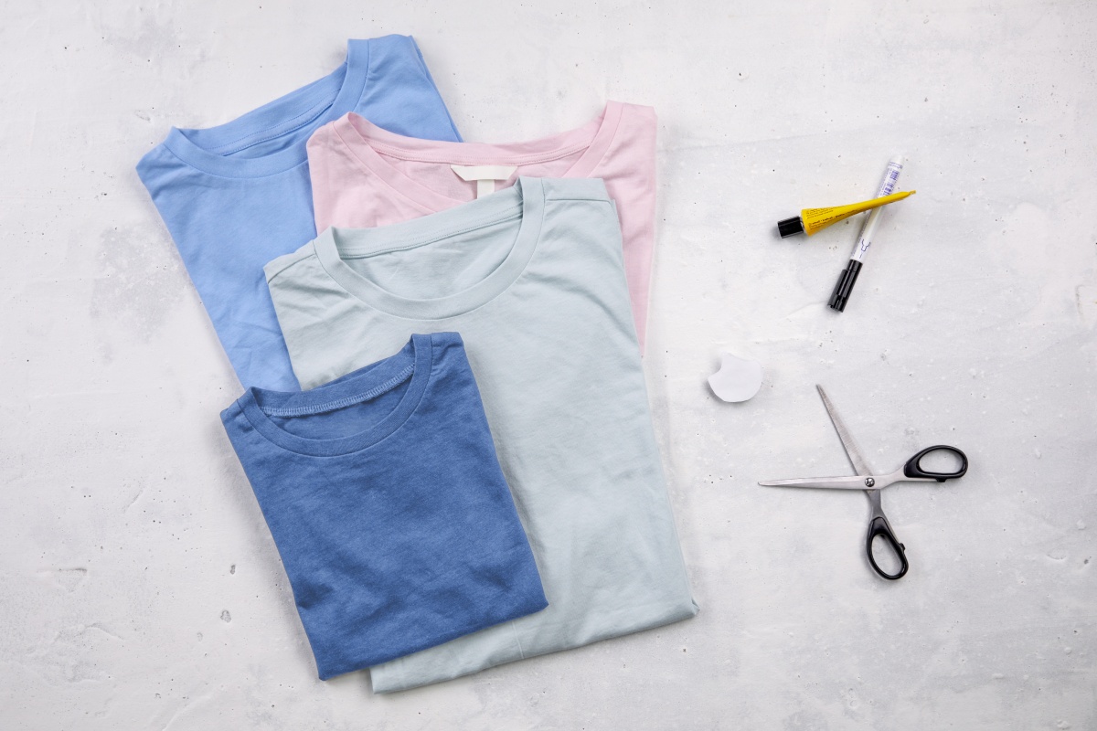 Ein Stapel alter T-Shirts, eine Schere, Kleber und ein Stift um Regenbogenfisch-Kostüm selber zu machen.