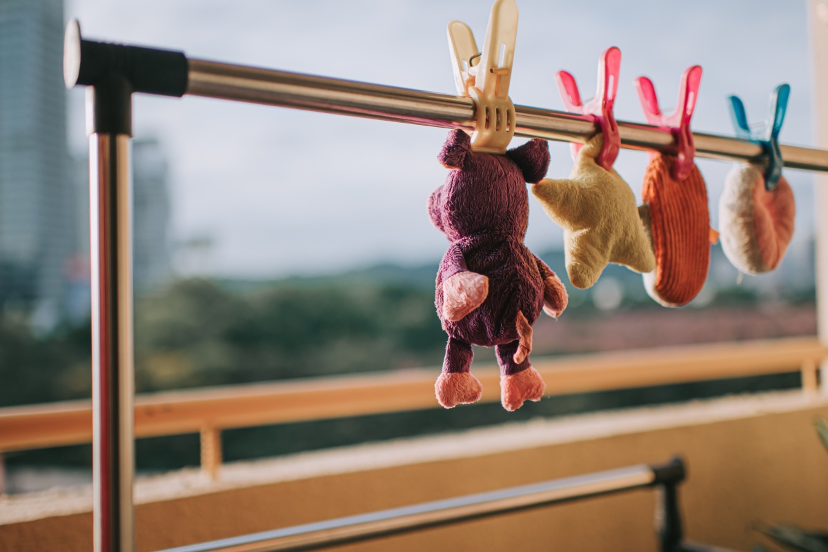 Frisch gewaschene Kuscheltiere hängen zum Trocknen in der Sonne auf einem Balkon.