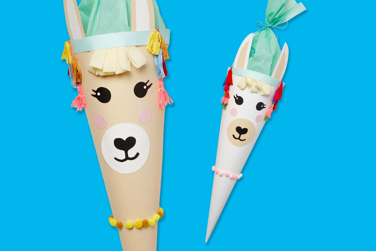 Zwei Schultüten in Lama-Design mit bunten Quasten und Gesicht vor blauem Hintergrund.