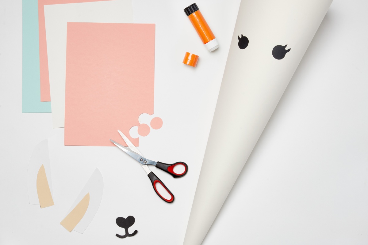 Farbiges Papier, Schere, Klebestift und Schultüten Rohling.