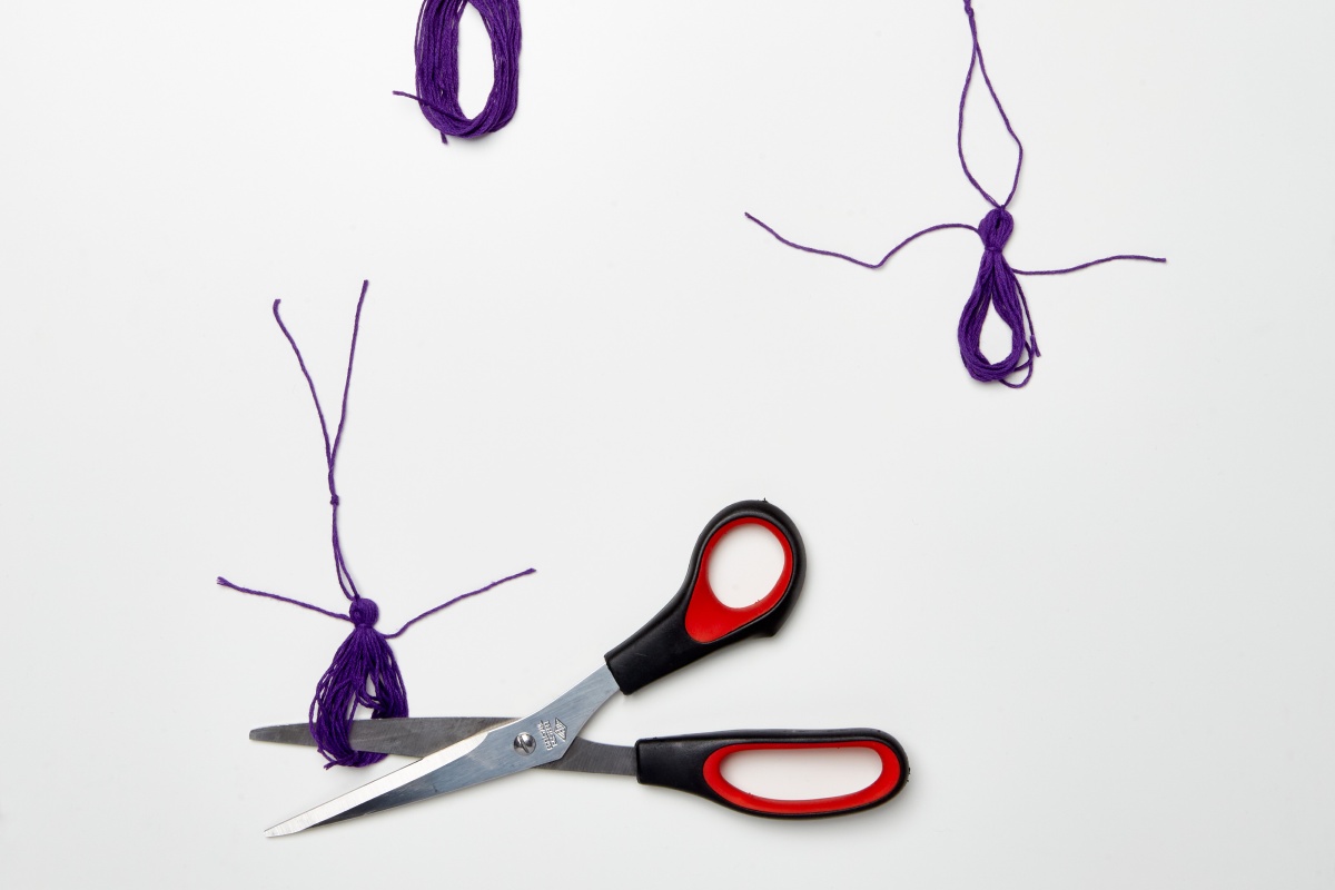 Quasten für die Schultüte basteln mit Schere und Knoten.