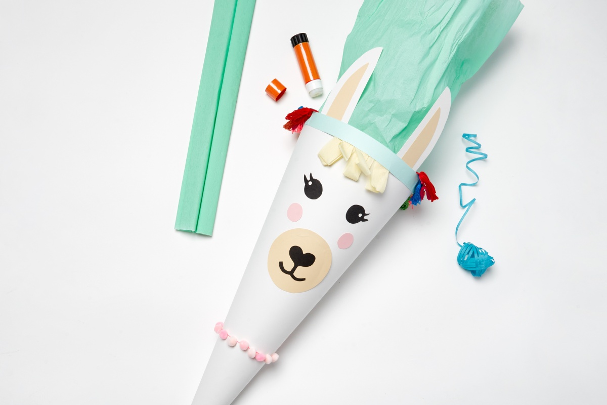 Fertig gebastelte Schultüte im Lama-Design mit grünem Krepppapier, Quasten und Pompons..
