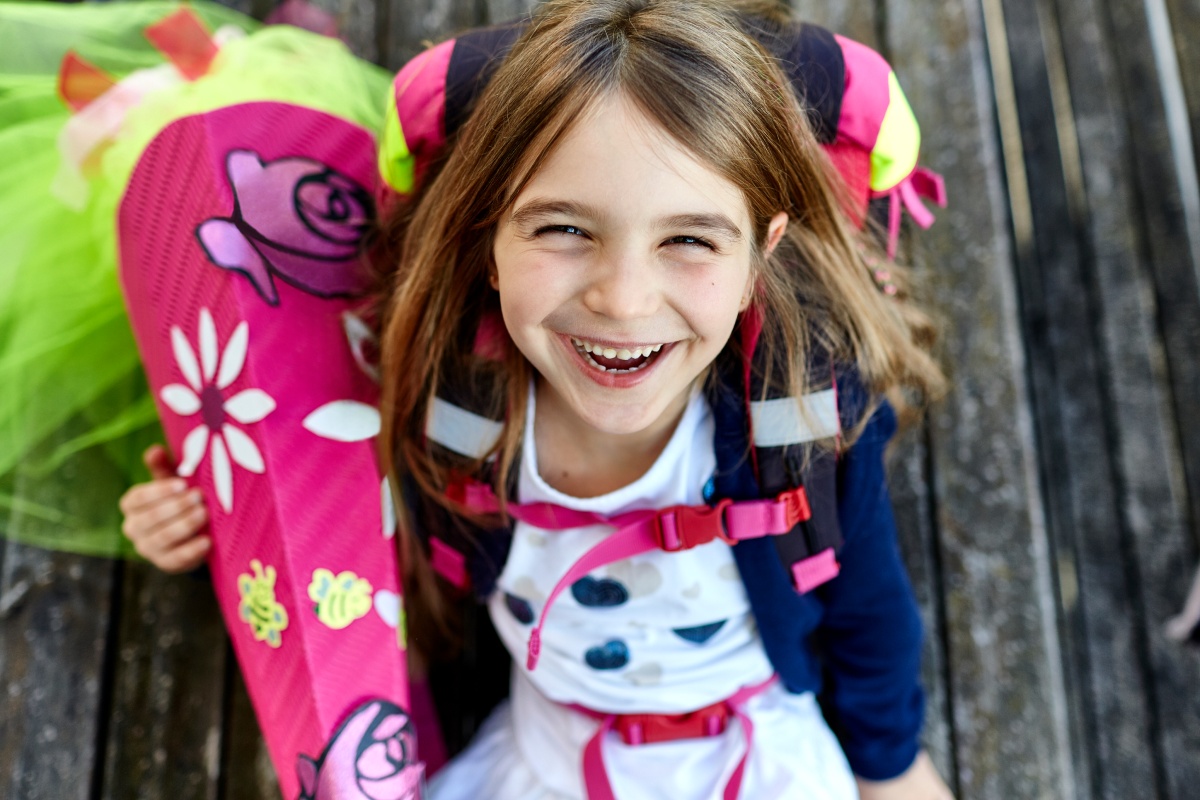 Lächelndes Mädchen mit befüllter Schultüte und Rucksack.