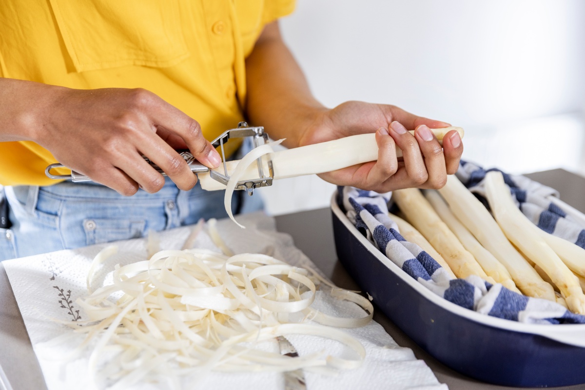 Eine Person schält weißen Spargel.