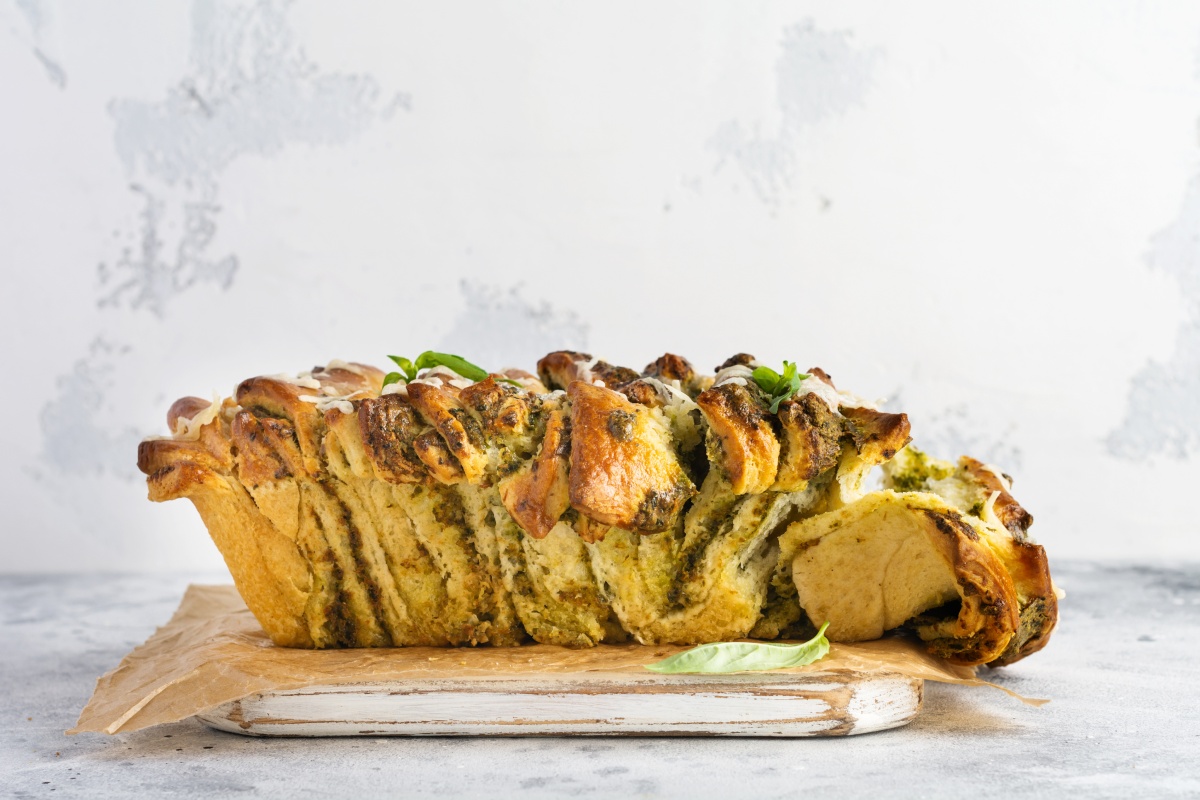 Ein vegetarisches Pull-apart-Brot mit Pesto und Kräutern auf einem Teller.