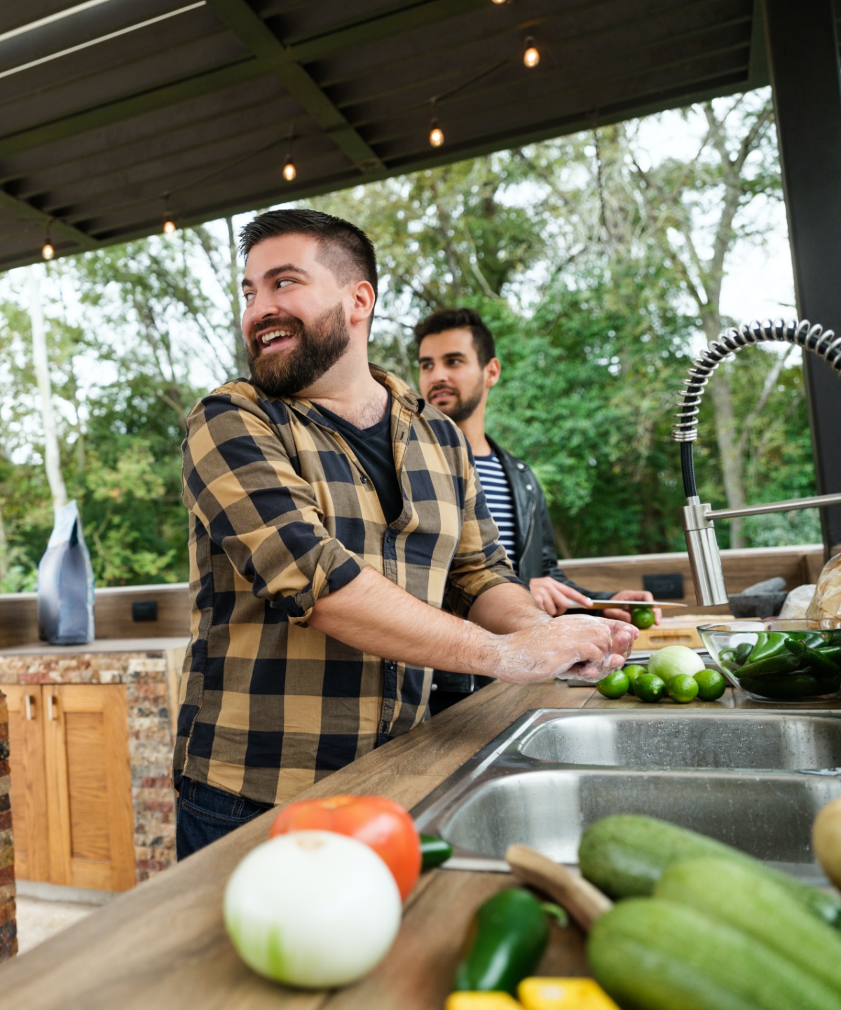 Zwei Männer bereiten in der Outdoorküche Essen zu
