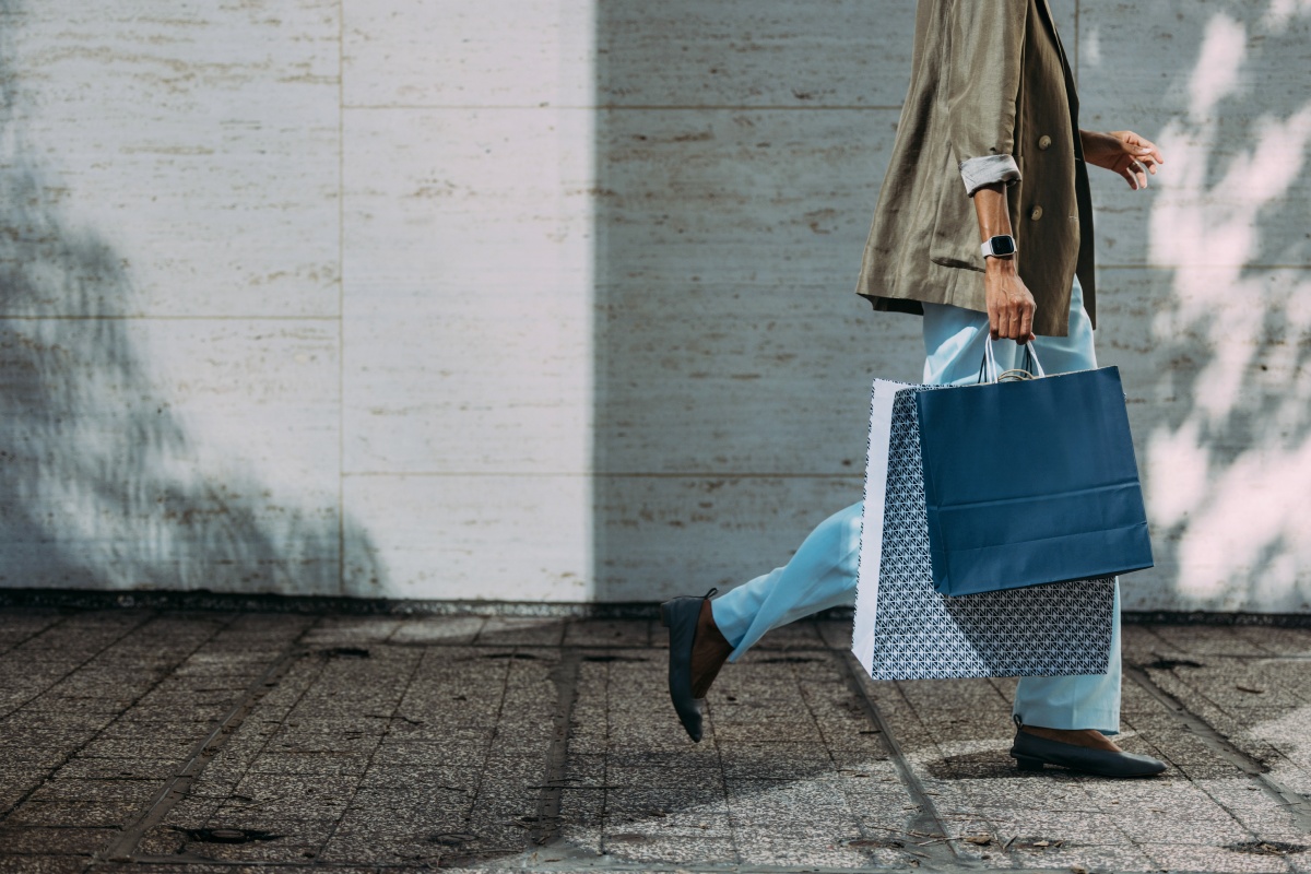 Person läuft mit großen Einkaufstüten den Gehweg entlang.