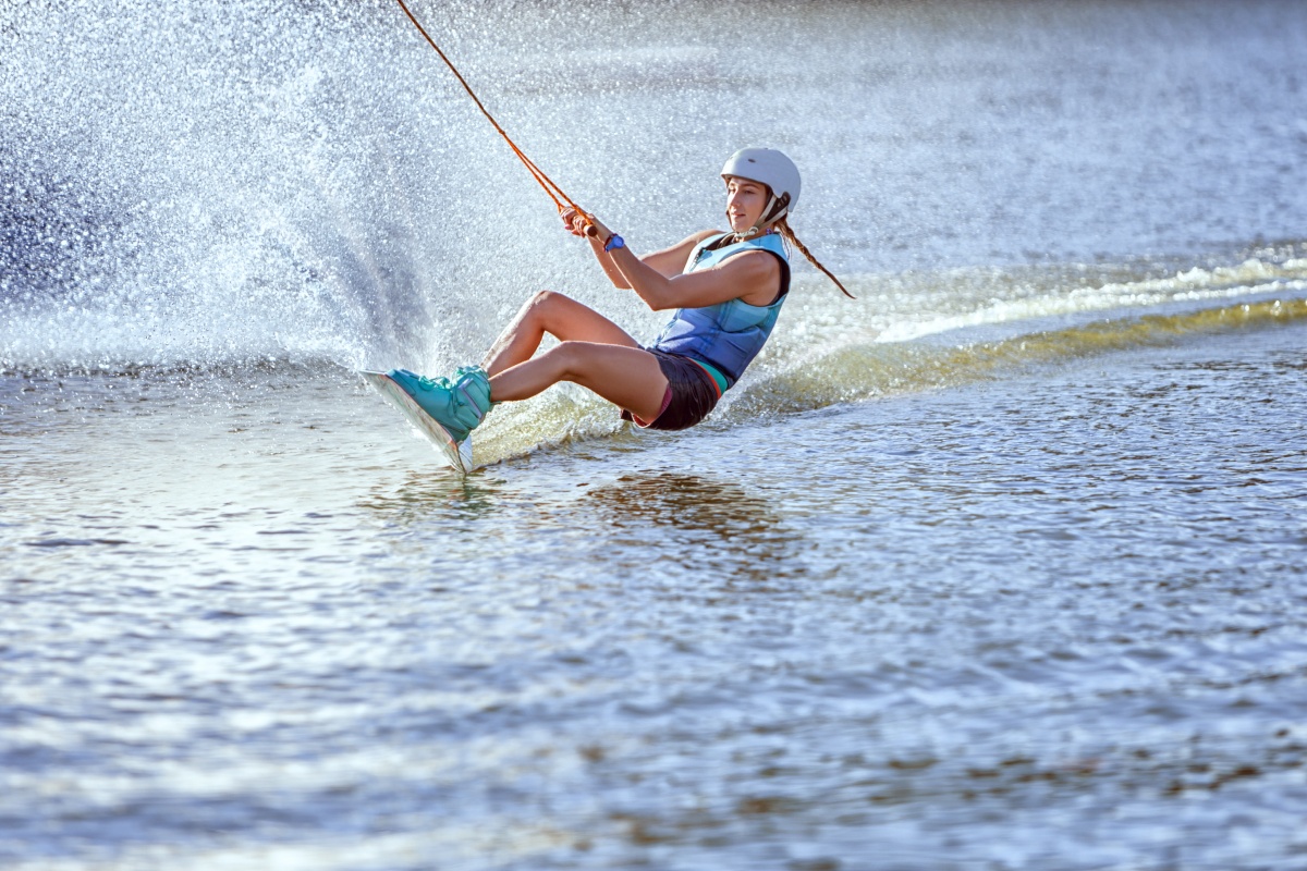 Frau mit Helm beim Wakeboarding auf dem Wasser.
