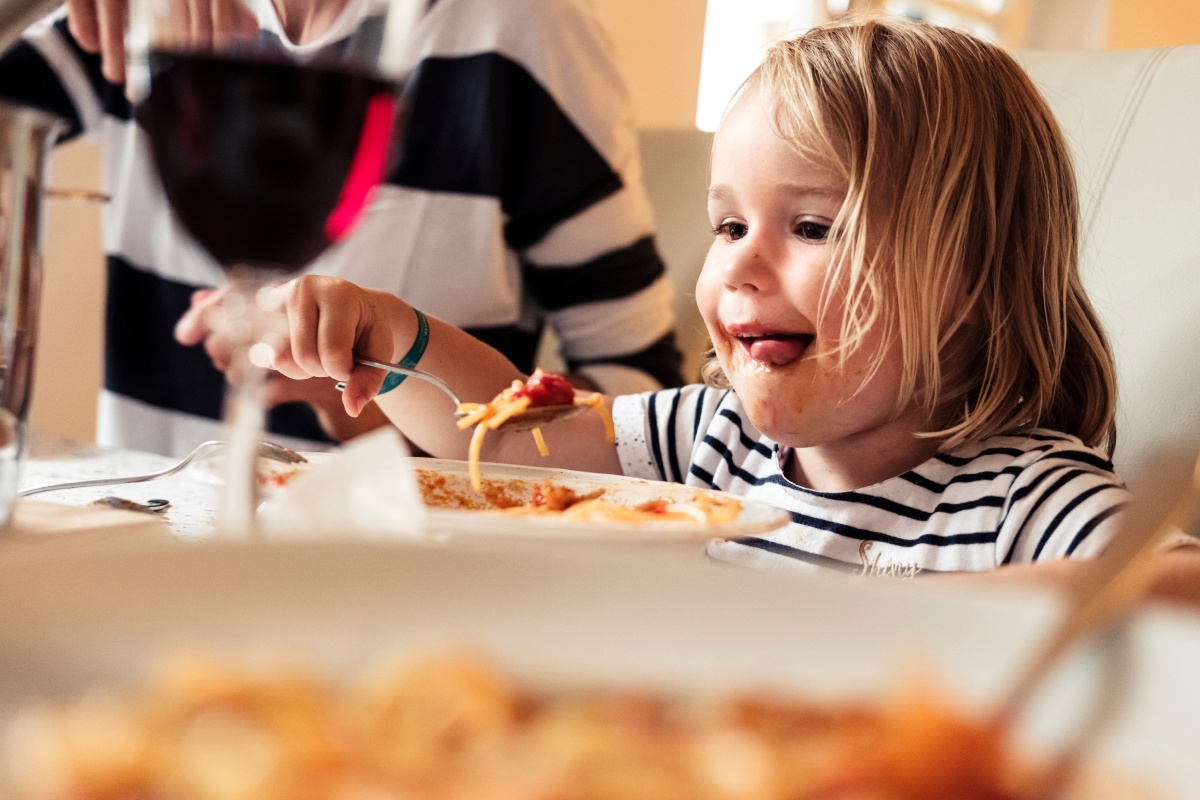 Kleines Kind isst begeistert Spaghetti und schaut konzentriert auf den Teller.