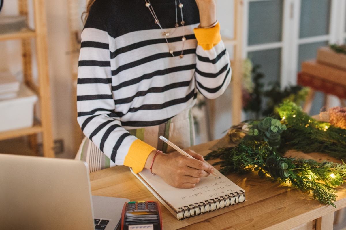 Eine junge Frau macht sich Notizen darüber, was sie sich kochen möchte.