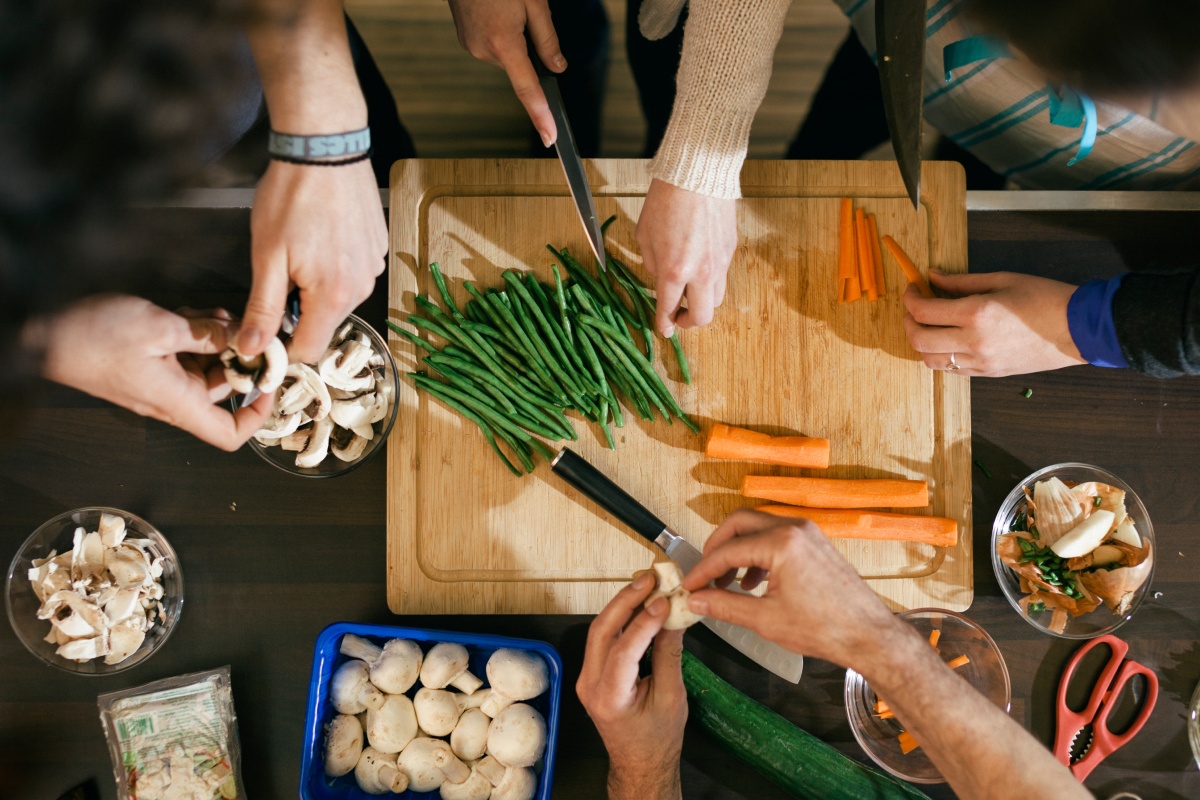 Vier Personen bereiten zusammen ein Rezept zu.