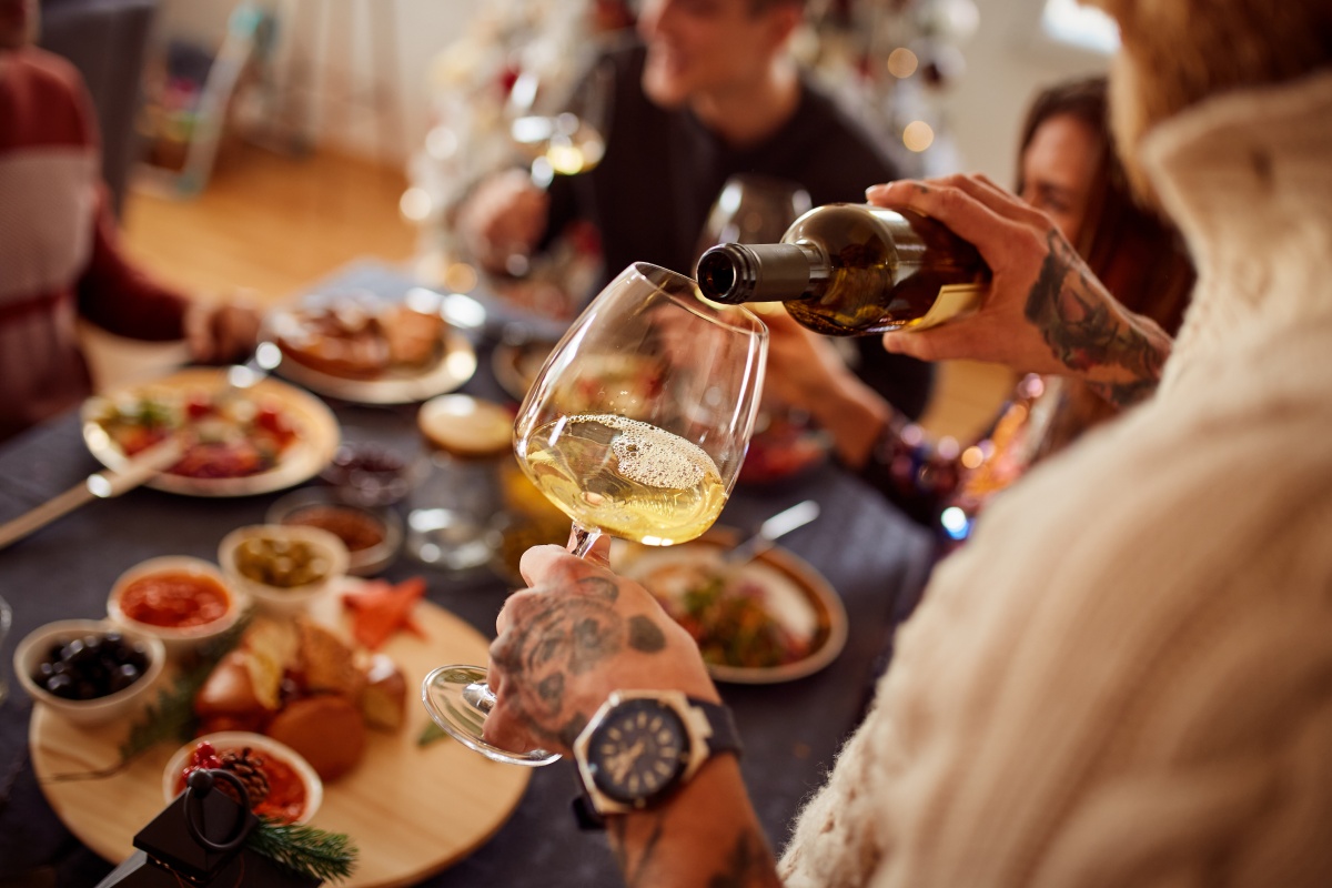Eine Person schenkt sich gerade ein Glas Wein zum Abendessen ein.