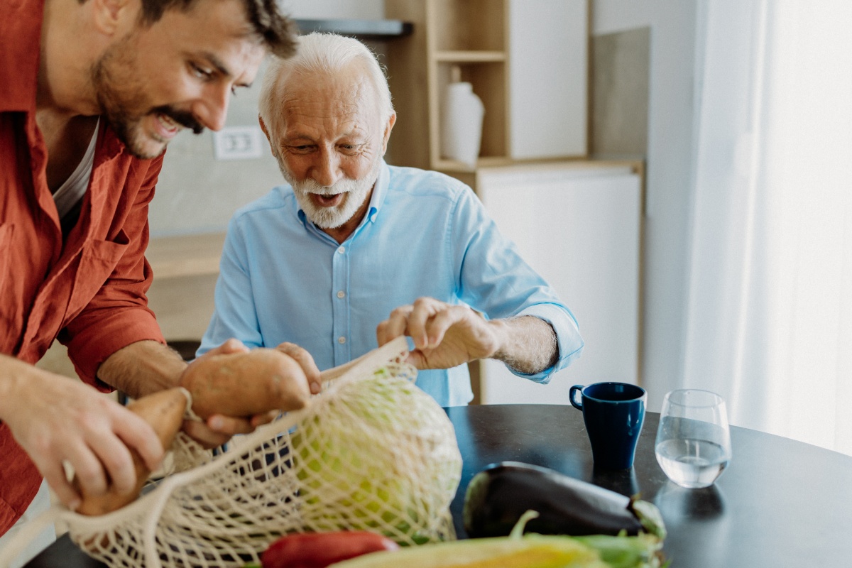 Älterer Mann und jüngerer Mann packen gemeinsam frisches Gemüse aus.