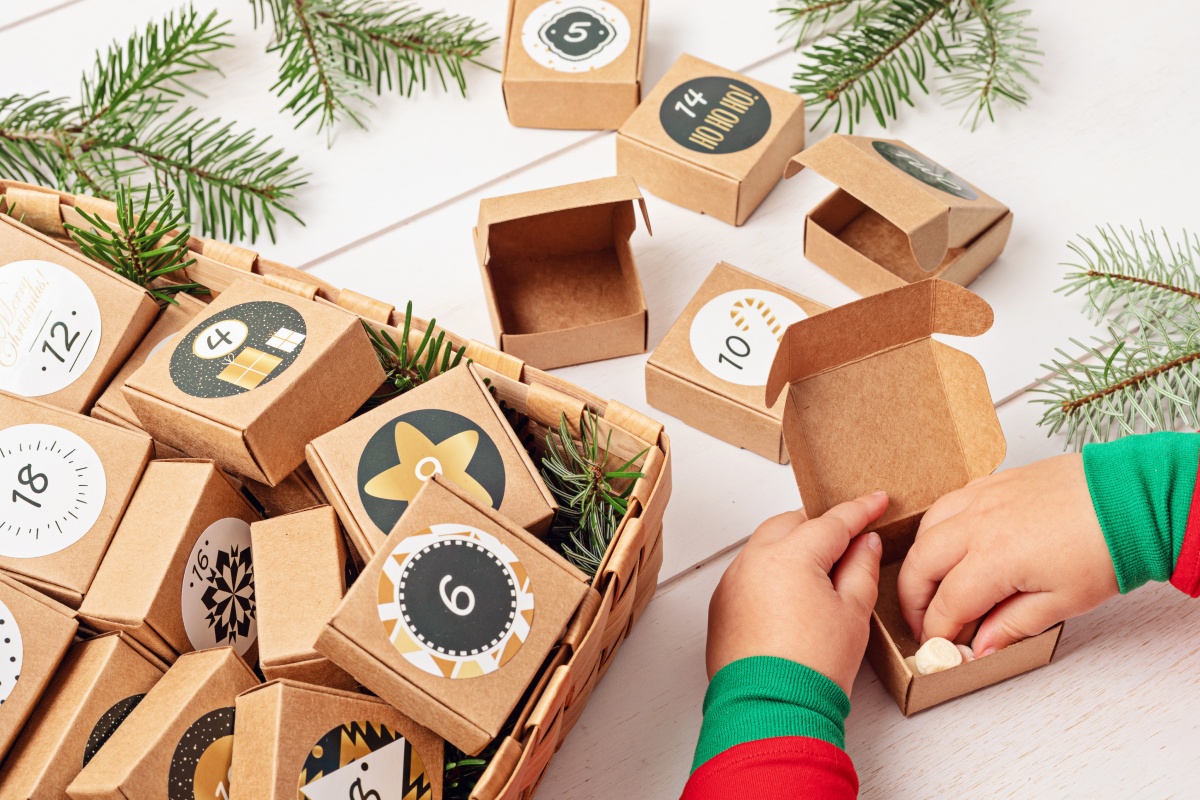 Kinderhände öffnen eine Adventsbox aus einem selbst befüllten Adventskalender.