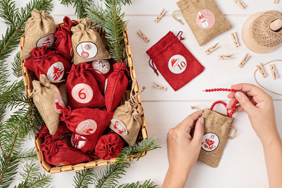 Eine Person befüllt einen kleinen Stoffbeutel mit einer Perlenkette, als Teil eines selbstbefüllten Adventskalender.