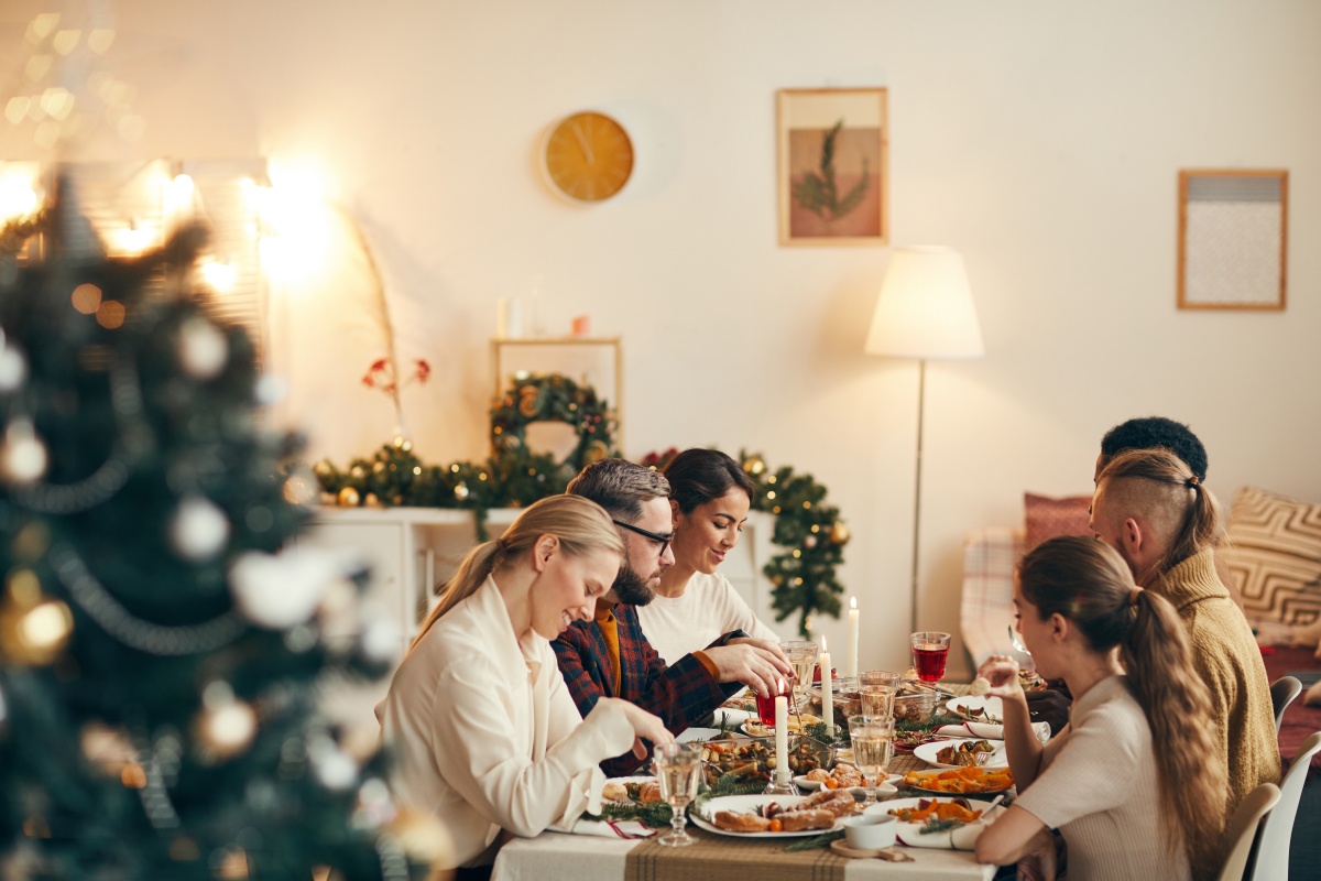 Familie sitzt an festlich gedecktem Tisch und genießt das Weihnachtsessen.