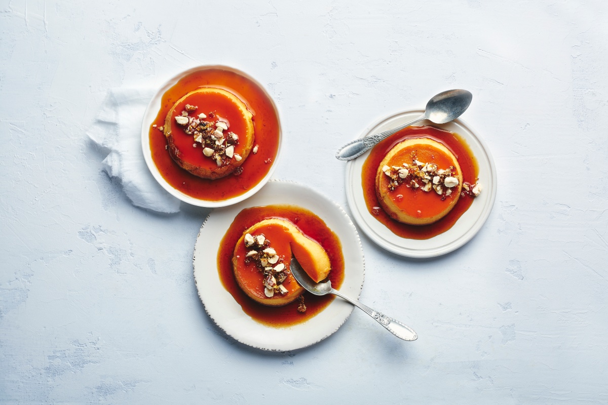 Karamellflan mit gehackten Nüssen auf drei Tellern serviert.