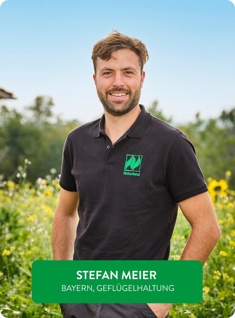 Naturland-Landwirt Stefan Meier steht vor einer blühenden Anbaufläche.