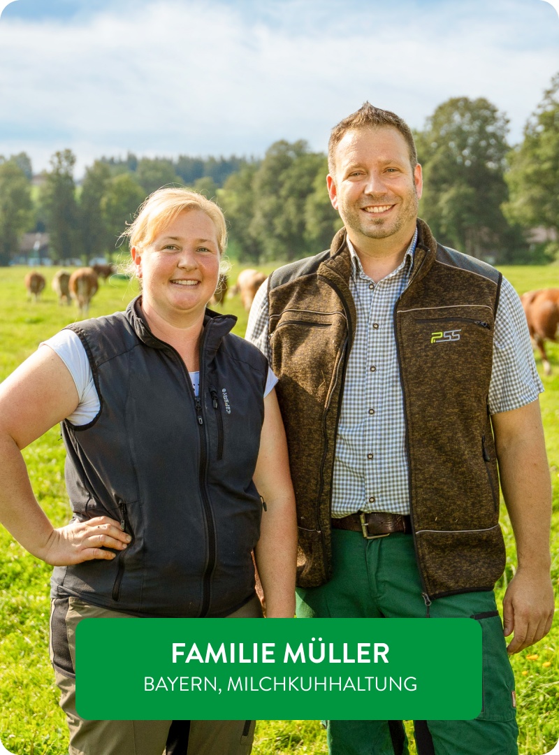 Naturland-Landwirte Herr und Frau Müller vor einer Kuhherde auf der Wiese.