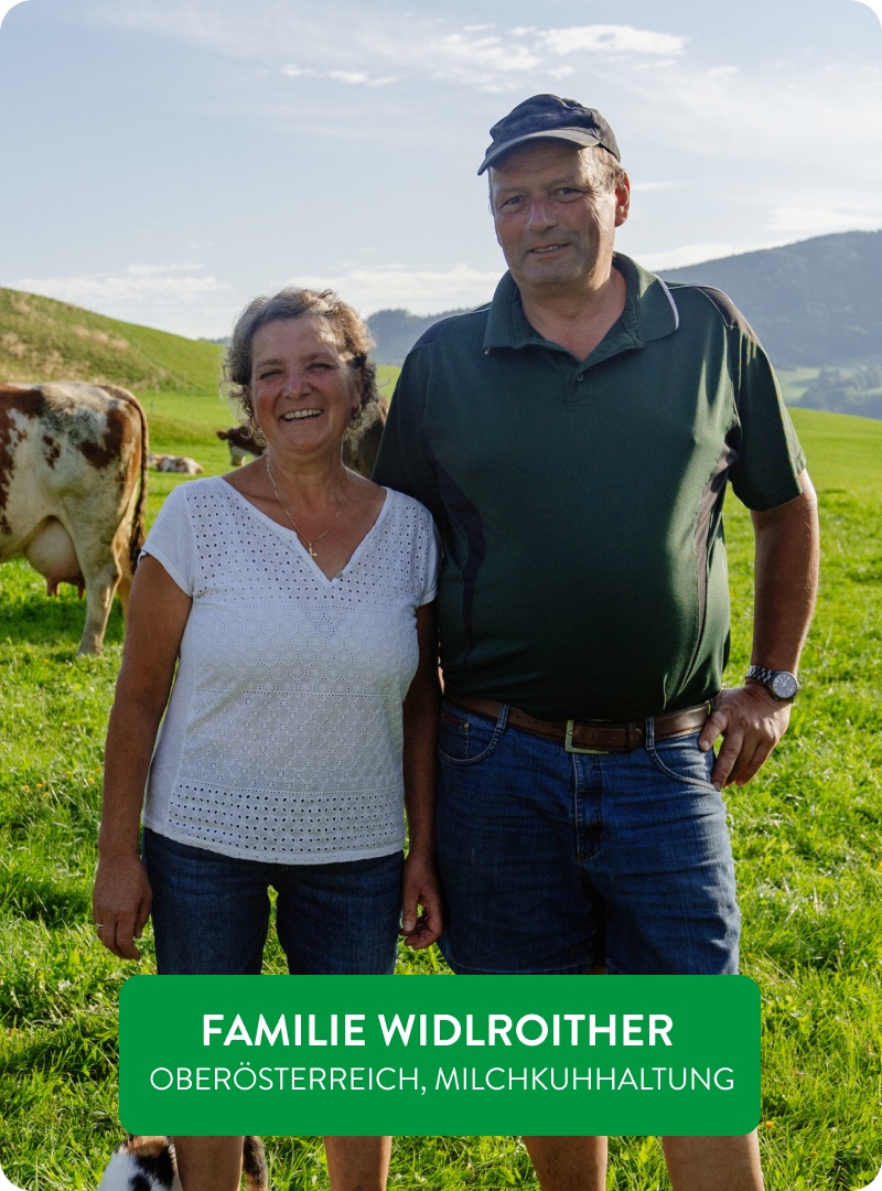 Naturland-Landwirte Herr und Frau Widlroither stehen mit ihren Kühen auf einer Wiese.