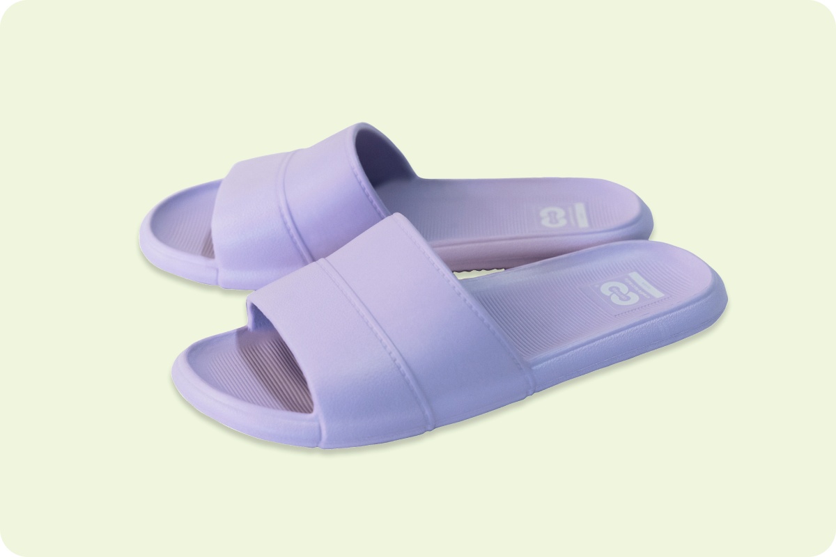 Lila Pantoletten aus Kunststoff auf hellem Hintergrund.