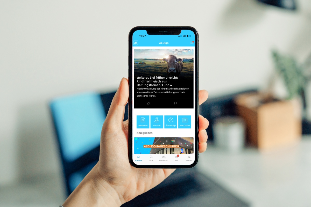 Eine Hand hält ein Smartphone mit geöffneter ALDIgo Mitarbeitenden-App.