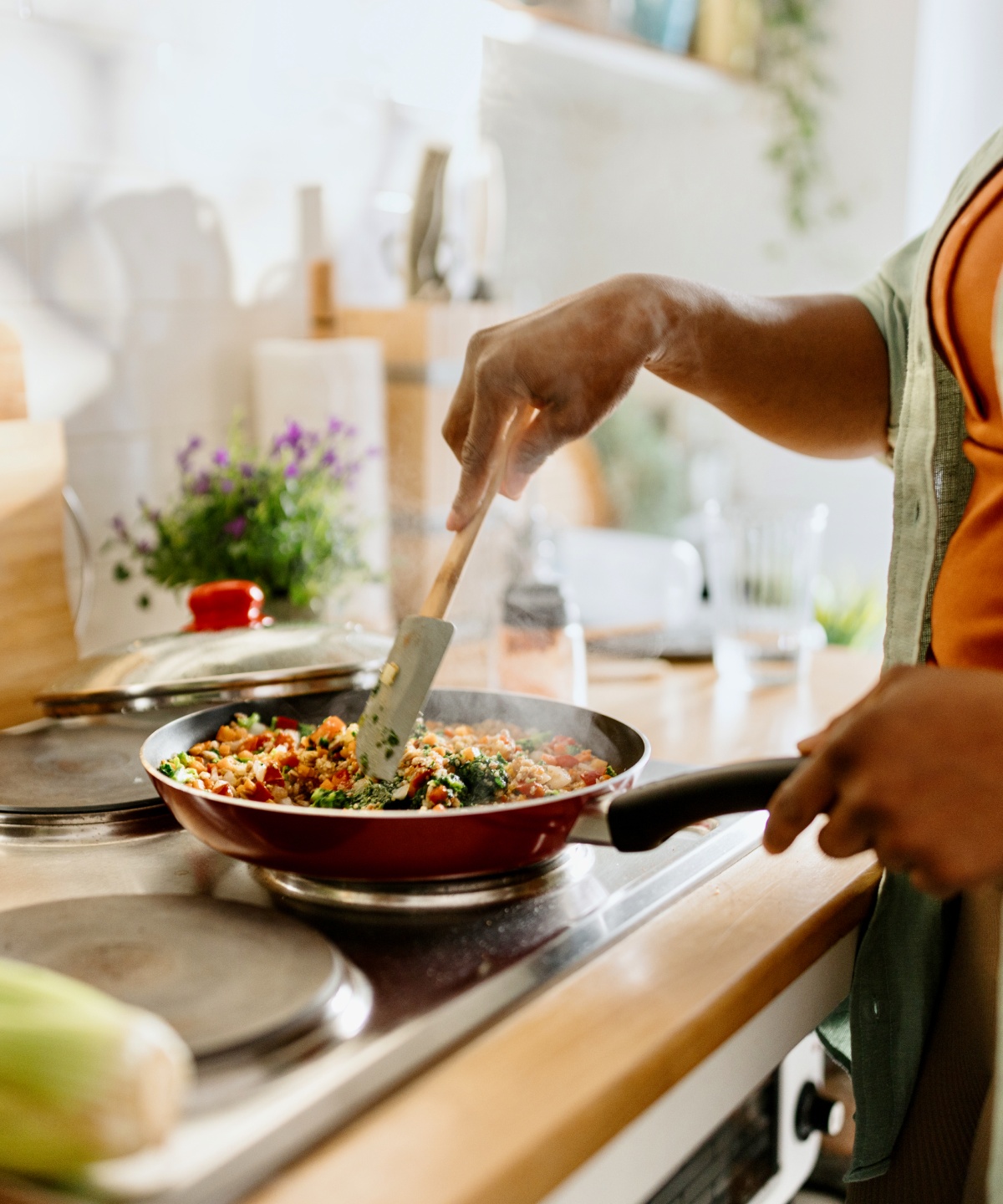Person kocht Gemüse in einer Pfanne auf dem Herd.