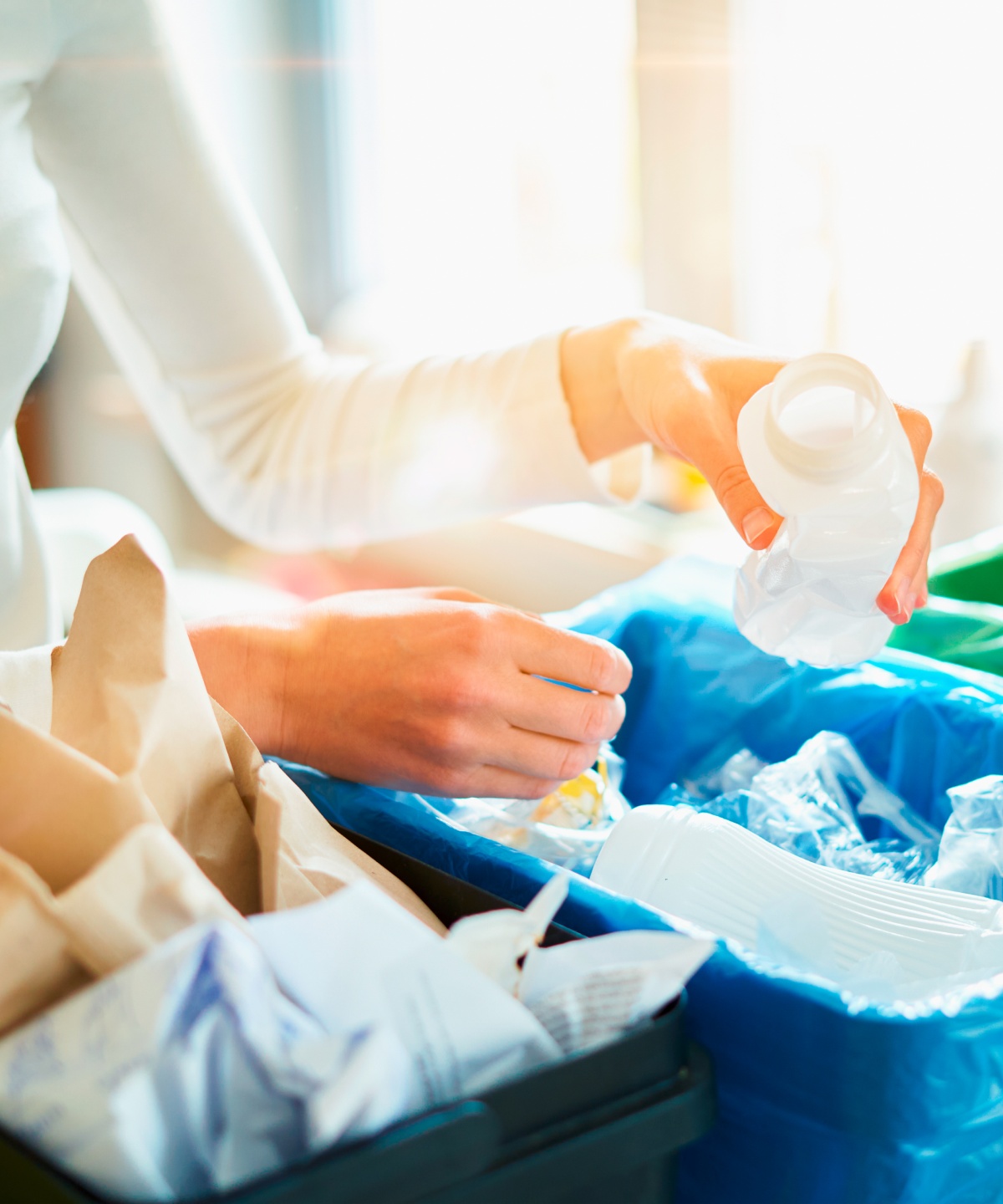 Eine Person ist gerade dabei, verschiedene Verpackungen in die Entsprechenden Recycling Behälter zu sortieren.