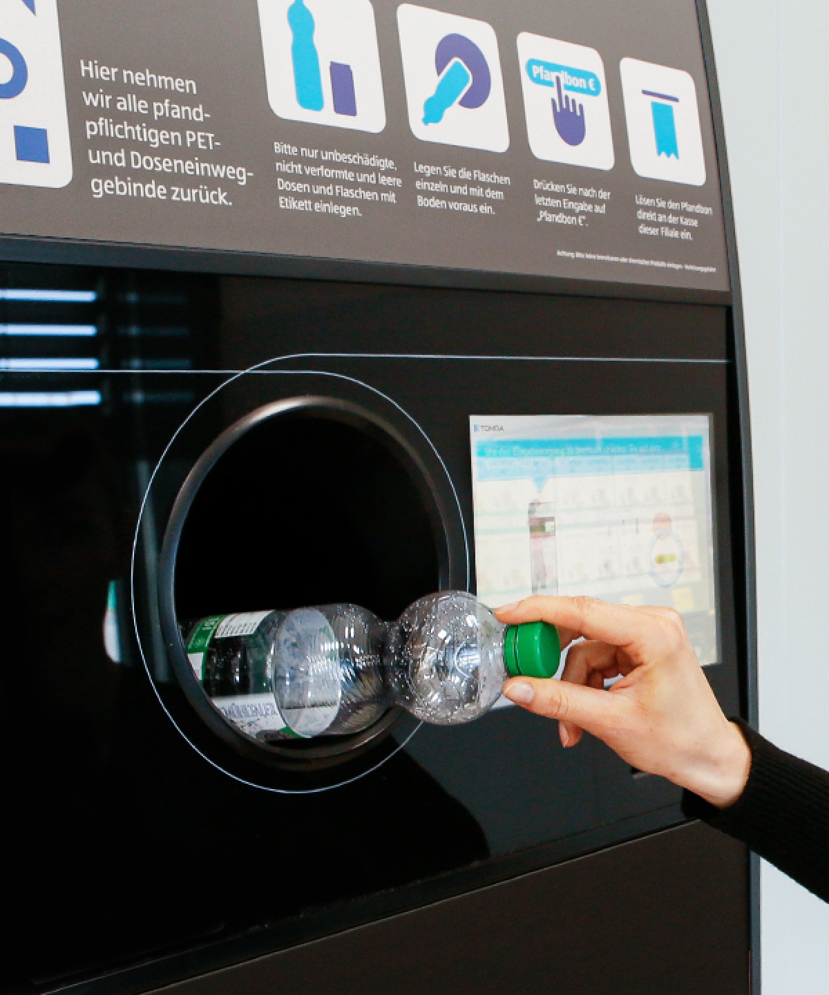 Eine Person recyclet gerade eine PET Flasche an einem ALDI SÜD Getränkeautomaten.