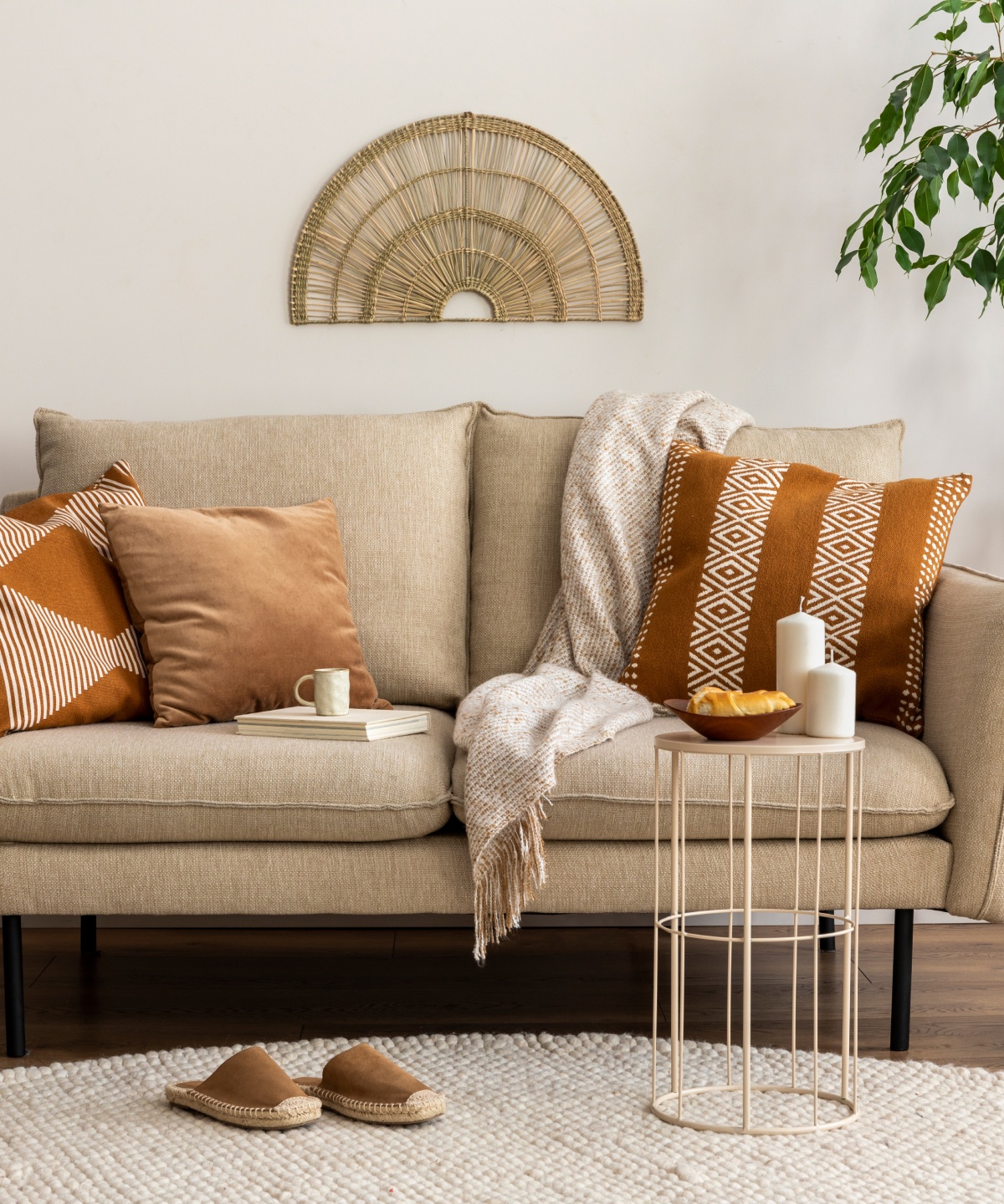 Ein helles Sofa im trendigen Boho-Stil mit Kissen, Decken und Accessoires