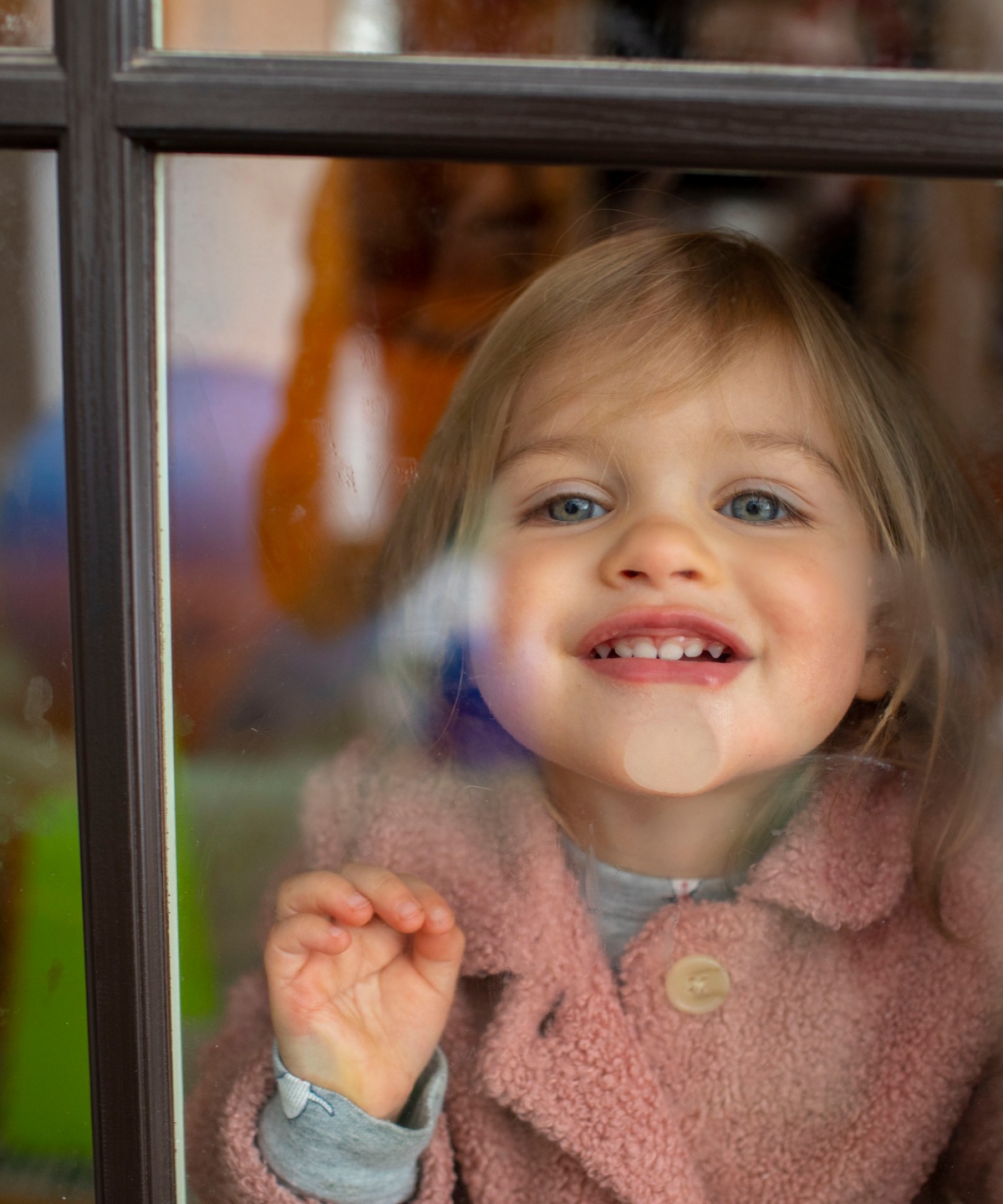 Ein kleines Mädchen presst ihr Gesicht gegen eine frisch geputzte Fensterscheibe.