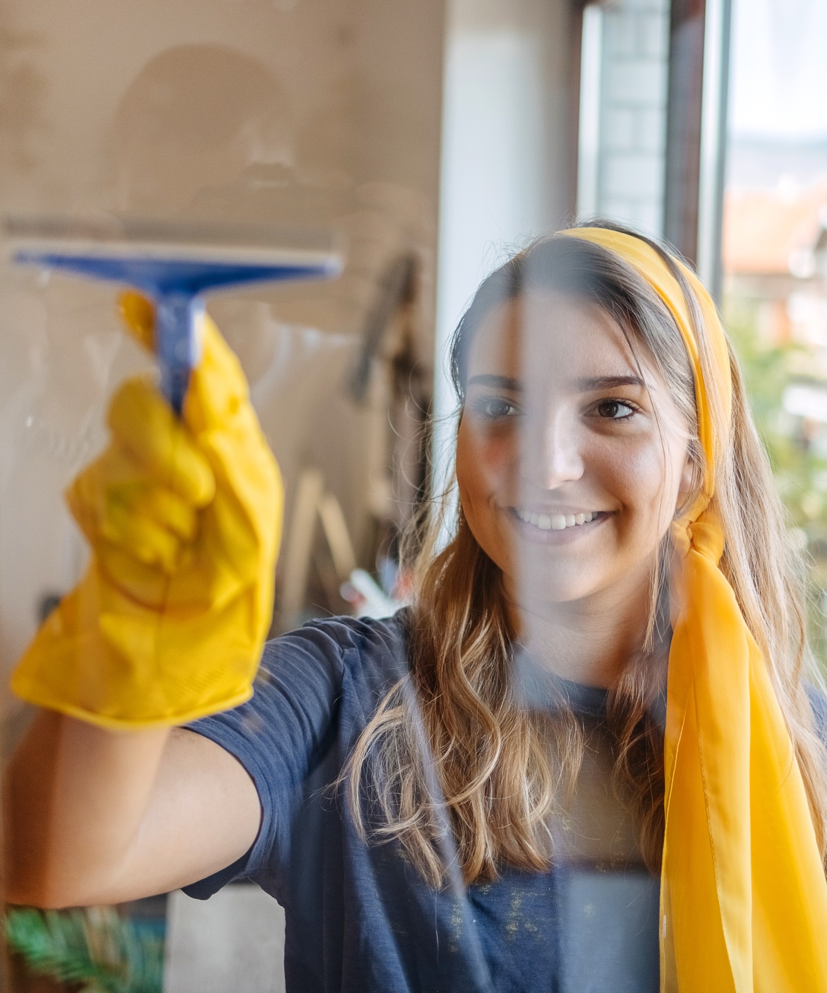 Eine Frau putzt ihre Scheiben mit einem Abzieher.